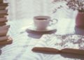 Books and an open book on a table next to a cup of coffee