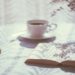 Books and an open book on a table next to a cup of coffee