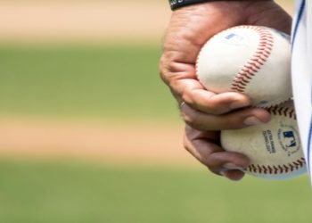 Close-up of a person holding two baseballs