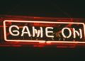Bright neon sign reading "Game On," illuminating the surrounding area with vibrant colors.