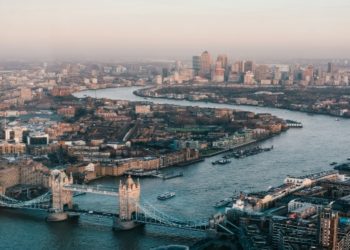 Panoramic view of London's skyline featuring iconic buildings like the Shard and the London Eye against a clear sky