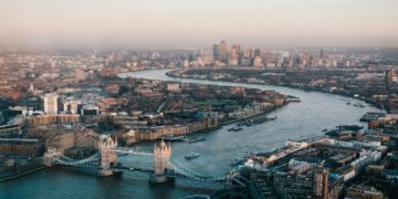 Panoramic view of London's skyline featuring iconic buildings like the Shard and the London Eye against a clear sky