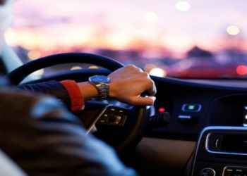 Man driving a car at night, focused on the road with one hand on the steering wheel.