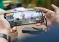 Close-up of a person gripping a smartphone with a mobile game on the screen, highlighting mobile gaming culture.