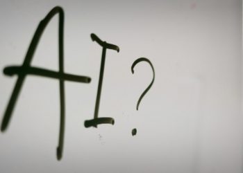 Whiteboard displaying the word "AI" with a question mark, suggesting a discussion about artificial intelligence.