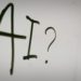 Whiteboard displaying the word "AI" with a question mark, suggesting a discussion about artificial intelligence.