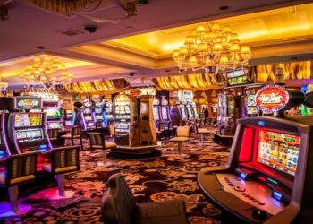 Vibrant casino room filled with numerous slot machines and colorful lights illuminating the space.