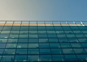 Sleek building featuring glass windows against a bright blue sky.