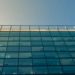 Sleek building featuring glass windows against a bright blue sky.