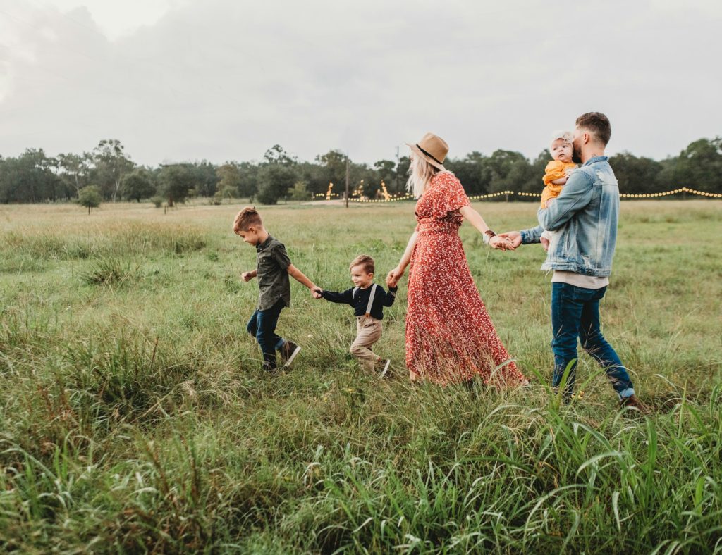 Joyful family strolls through a vibrant green field, embracing the beauty of nature together.