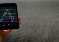 Smartphone displaying a stock chart with fluctuating lines and data points.