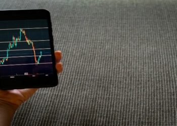 Smartphone displaying a stock chart with fluctuating lines and data points.