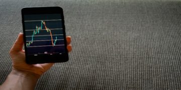Smartphone displaying a stock chart with fluctuating lines and data points.
