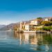 Scenic view of Lake Como featuring a majestic castle surrounded by lush greenery and tranquil waters.