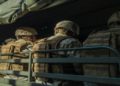 Marines seated in the back of a military truck, wearing uniforms and gear, ready for deployment.