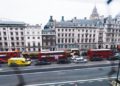 Looking out from a window at a vibrant UK city street, with vehicles and people navigating the urban landscape.