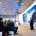 Speaker at the World Economic Forum presents data on a large screen in a modern conference room. Attendees sit attentively, creating an engaged atmosphere.