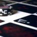 Stack of black and white poker chips sits on a table surrounded by a spread of dark playing cards adorned with red and white symbols, conveying a sense of strategy.