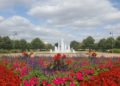 Vibrant flower garden with red and pink blooms, purple accents, and a central fountain in Hertfordshire, England