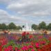 Vibrant flower garden with red and pink blooms, purple accents, and a central fountain in Hertfordshire, England