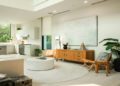 Bright, modern living room with a cream sofa, circular white rug, and a wooden sideboard. Large windows and plants add a fresh, airy feel.