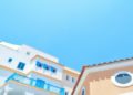 Orange and white Mediterranean buildings with blue railings under a clear sky in Limassol, Cyprus. The bright colors and sunny day evoke a cheerful, tranquil vibe.