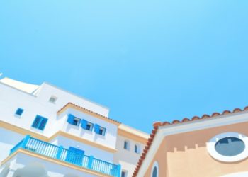 Orange and white Mediterranean buildings with blue railings under a clear sky in Limassol, Cyprus. The bright colors and sunny day evoke a cheerful, tranquil vibe.