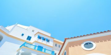 Orange and white Mediterranean buildings with blue railings under a clear sky in Limassol, Cyprus. The bright colors and sunny day evoke a cheerful, tranquil vibe.