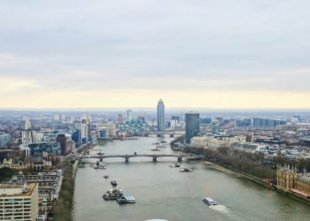 Aerial view of London shows Thames River, bridge, and cityscape with modern and historic buildings