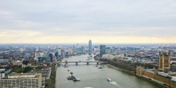Aerial view of London shows Thames River, bridge, and cityscape with modern and historic buildings