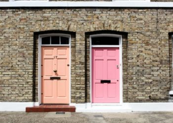 Two vibrant doors on a brick townhouse; left door is peach, numbered 17, and right door is bright pink in London, United Kingdom. The scene is sunny and inviting.