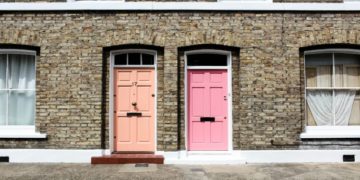 Two vibrant doors on a brick townhouse; left door is peach, numbered 17, and right door is bright pink in London, United Kingdom. The scene is sunny and inviting.
