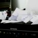 Cluttered Epson printer covered with crumpled and folded paper, creating a disorganized and chaotic appearance, suggesting frustration or a busy work environment.