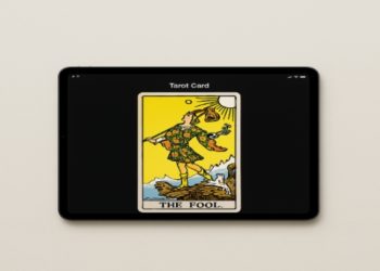 Tarot card depicts "The Fool" on a tablet screen. The card illustrates a carefree figure near a cliff, under a bright yellow sky, evoking a sense of adventure.
