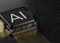 Microchip with the letters "AI" is resting on a dark, textured surface. Gold circuit lines extend from the chip, portraying a high-tech, futuristic feel.