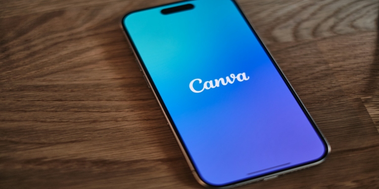 Smartphone on a wooden table displaying the Canva app with a blue to purple gradient background, conveying a modern, creative vibe.