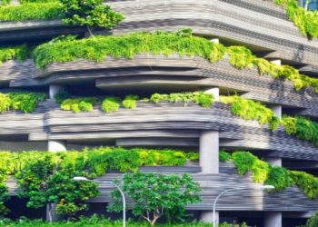Modern multi-story building with balconies adorned with lush green plants. Curved lines and abundant greenery give it an eco-friendly, vibrant feel.