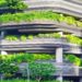 Modern multi-story building with balconies adorned with lush green plants. Curved lines and abundant greenery give it an eco-friendly, vibrant feel.