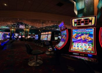 Lively casino interior with rows of colorful slot machines and barstool seating. The ceiling is adorned with twinkling lights, creating an exciting atmosphere.