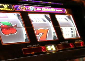 Close-up of a slot machine displaying cherries, the number 7, and a bar symbol. The machine shows a $1 play with two credits won, creating excitement.