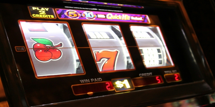 Close-up of a slot machine displaying cherries, the number 7, and a bar symbol. The machine shows a $1 play with two credits won, creating excitement.