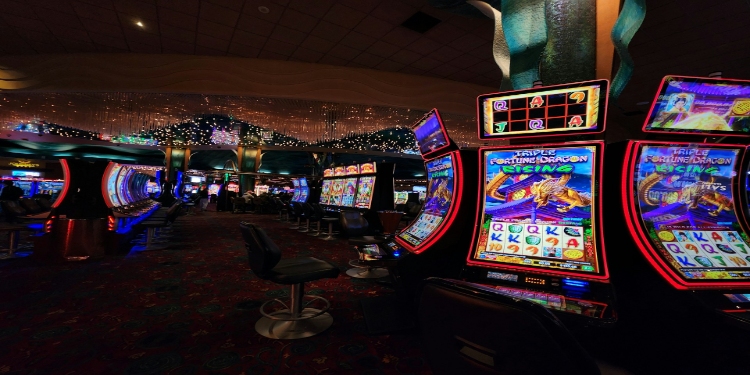 Lively casino interior with rows of colorful slot machines and barstool seating. The ceiling is adorned with twinkling lights, creating an exciting atmosphere.