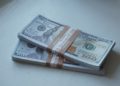 Stacks of $100 bills wrapped in brown bands lay on a white surface. The crisp notes convey a sense of wealth and financial abundance.