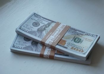 Stacks of $100 bills wrapped in brown bands lay on a white surface. The crisp notes convey a sense of wealth and financial abundance.