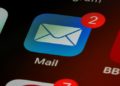 Close-up of a smartphone screen showing apps with a focus on the Mail app icon. The app displays a red notification badge with the number two, indicating new messages.
