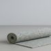 Rolled-up, speckled blue and gray carpet rests on a light gray surface with one edge unfurled. The minimalist setting conveys calm and simplicity.
