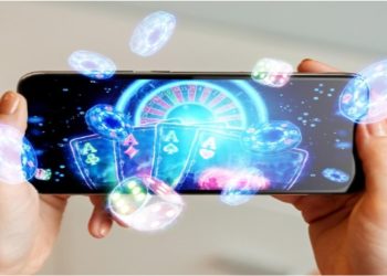 Hands holding a smartphone displaying a vibrant casino game with glowing poker chips, cards, and a roulette wheel, conveying excitement and entertainment.