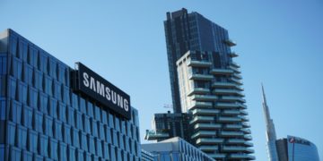 Modern cityscape with a Samsung building in the foreground, a tall residential tower, and additional skyscrapers against a clear blue sky.
