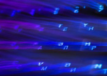 Blurred blue and purple glowing letters stream diagonally across a dark background, creating a dynamic, digital, and futuristic effect.