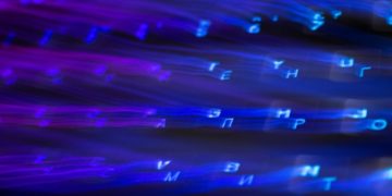 Blurred blue and purple glowing letters stream diagonally across a dark background, creating a dynamic, digital, and futuristic effect.